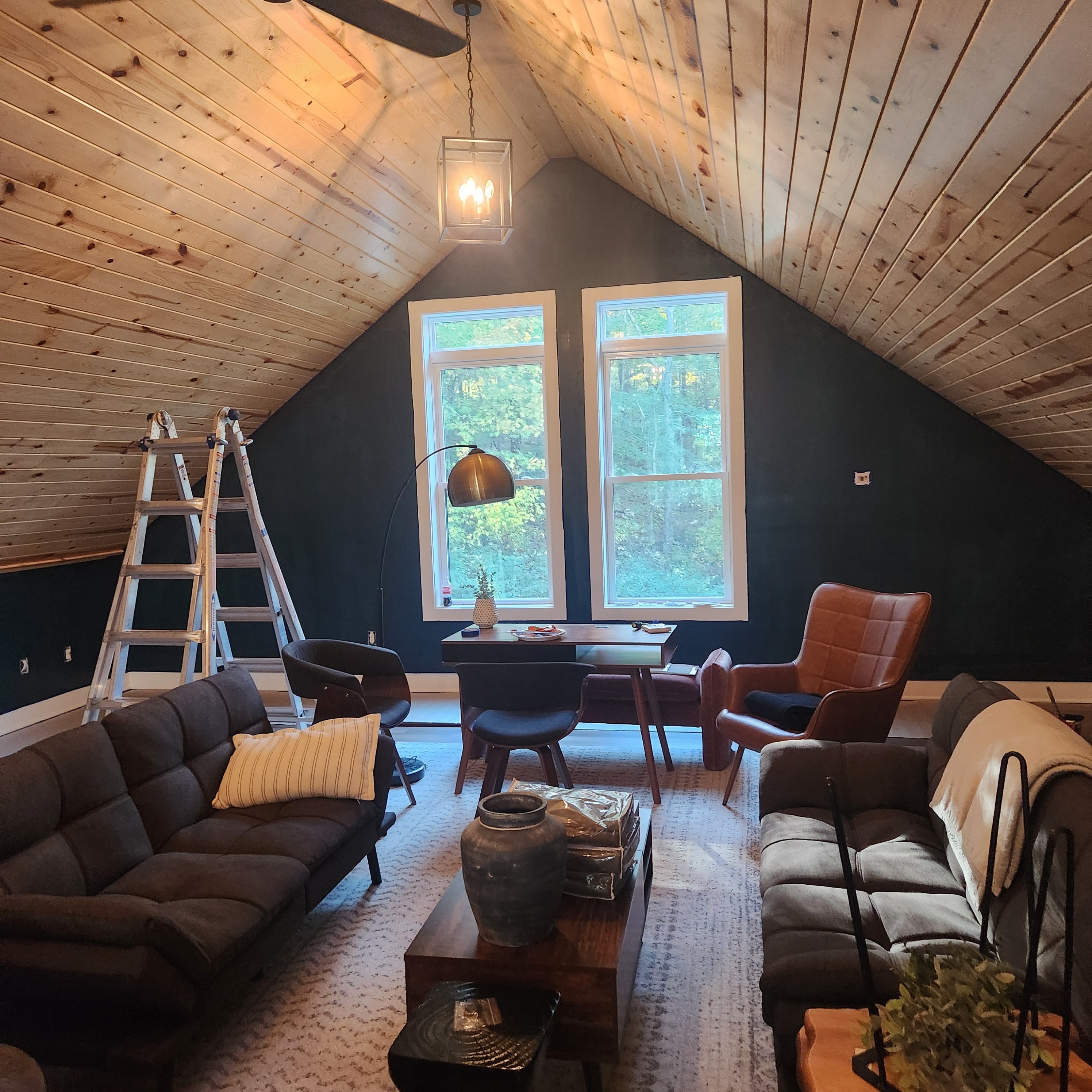 Cabin great room with deep green accent wall and wood plank ceiling